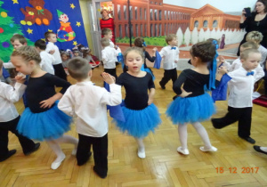 Na tle dekoracji światecznej dzieci tańczą w parach